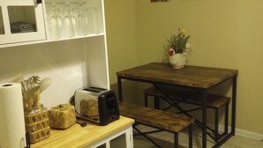 Une cuisine compacte avec une table en bois, un four encastré et un meuble blanc doté de portes en verre.
