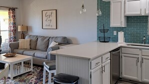 A modern kitchen with white cabinets, a central island, and a blue backsplash.