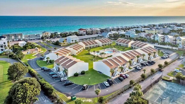 A coastal resort with multiple bungalow-style buildings, a central pool, and a parking area.