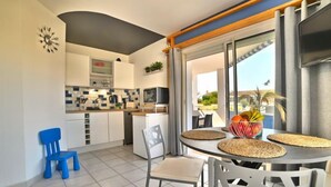 Een moderne keuken met witte kasten, een zwart aanrecht en een zithoek met een ronde tafel en stoelen.