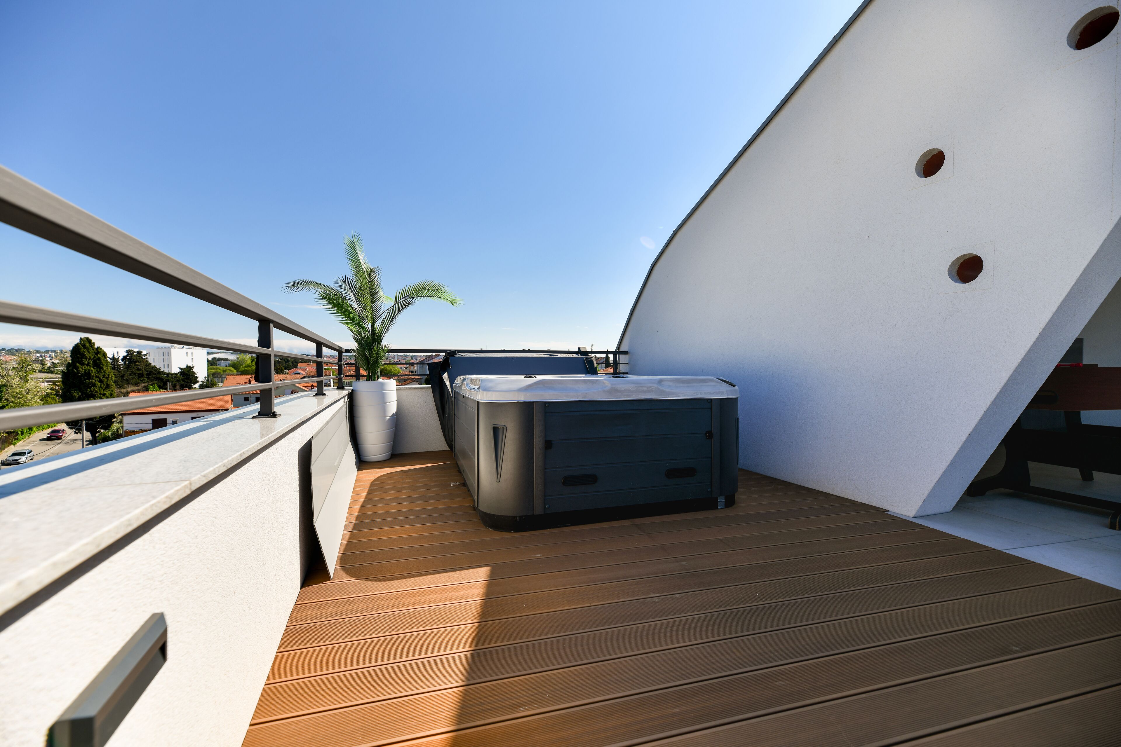 A balcony with a hot tub, wooden flooring, and a clear view of the cityscape.