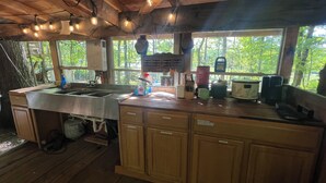 Una cocina rústica con armarios de madera, un lavamanos de acero inoxidable y una ventana con vistas a la vegetación.