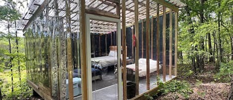 A glass-enclosed cabin with a bed, a small table, and a bench.