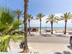 Blick auf einen Strand mit Palmen, einem Parkplatz und einem Gebäude mit Außenbereich.