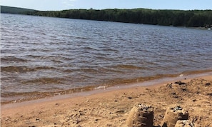 A beach with a sandy shore and a forested hill in the background.