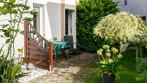 En terrasse med en trætrap, et bord med stole og en potteplante.