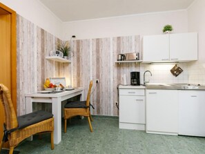 A compact kitchen with a dining area, white cabinetry, a coffee machine, and a small potted plant. - Apartment Tauber by Interhome (Zinnowitz)