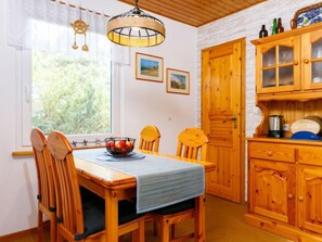 Ein Holzespeisekammer mit Stühlen, einer Obstschale und einem Fenster mit Vorhängen.