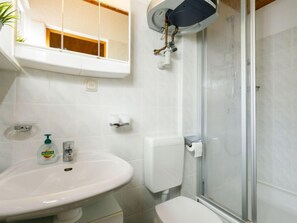 Ein Badezimmer mit weißem Waschbecken, Toilette und Duschkabine aus Glas.