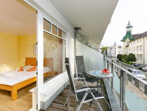 A balcony with a bed, a table with chairs, and a view of the city. - Luise von Preußen (App.101) by Interhome (Zinnowitz)