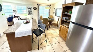 A kitchen with a central island, dining table, chairs, a refrigerator, and a window with blinds. - Spacious 5 Bedroom Home, two blocks to FSU. Oversized parking for up to 8 cars (Tallahassee)