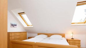 A bedroom with a wooden bed, two bedside tables, a nightstand, and skylights. - Vacation home Susi by Interhome (Koserow)