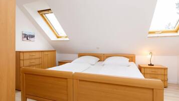 Ein Schlafzimmer mit einem hölzernen Bett, zwei Nachttischen, einem Schminktisch und Dachfenstern.