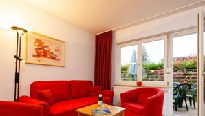 A red sofa set, a wooden coffee table, and a framed picture on the wall. - Vacation home Susi by Interhome (Koserow)