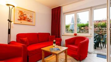 Eine rote Sofagarnitur, ein Holztisch und ein gerahmtes Bild an der Wand.