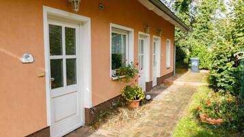Ein Haus mit einem Ziegelweg, der zum Eingang führt, umgeben von Grünpflanzen und Blumentöpfen.