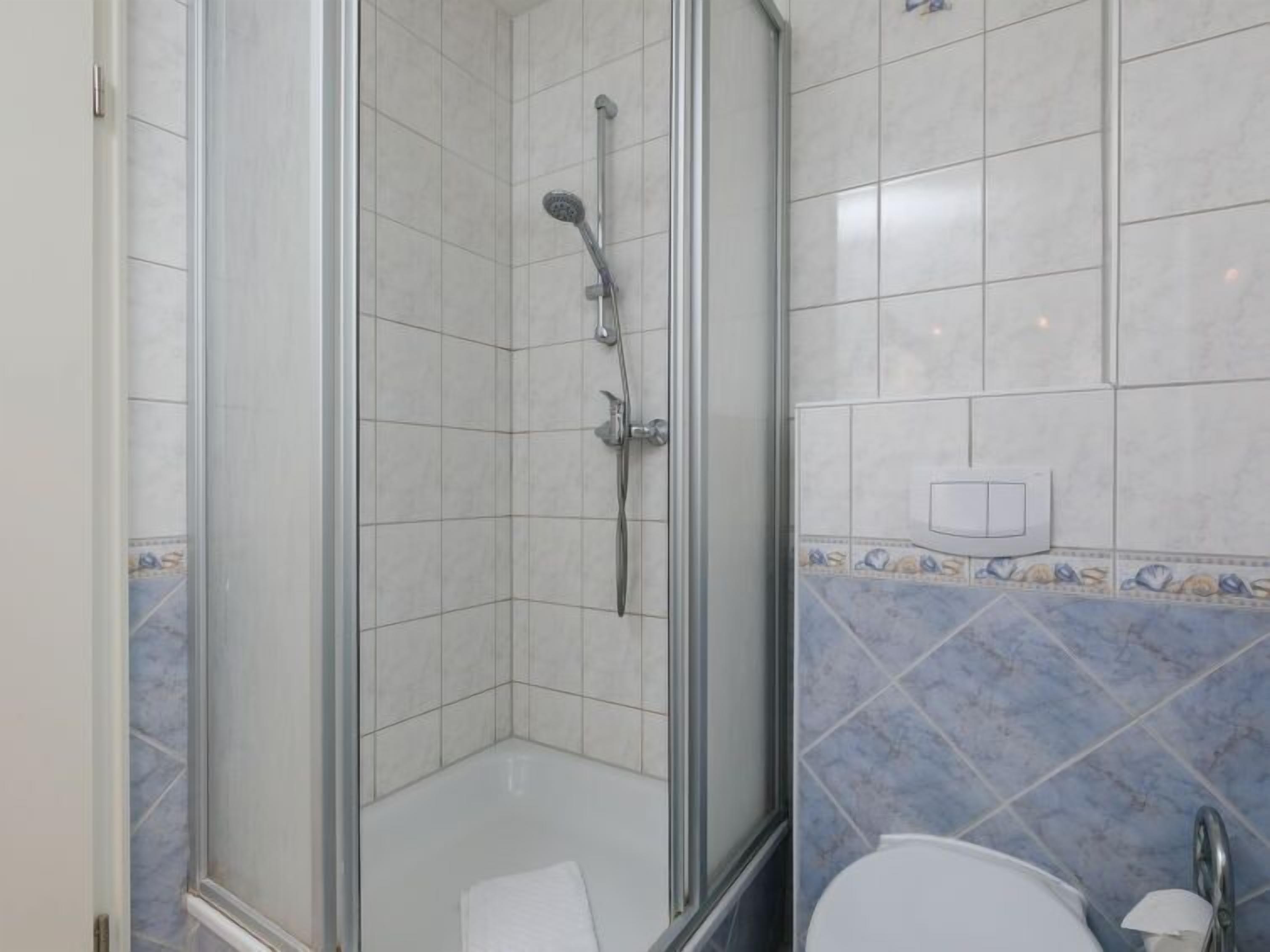 Ein Badezimmer mit Duschkabine, Toilette und gefliesten Wänden.