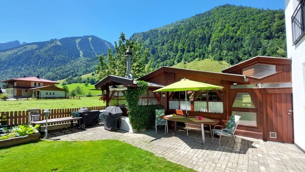 A wooden chalet with a patio area, a barbecue grill, and a view of a mountain. - Apartement Haus Dankl by Interhome (Fusch)