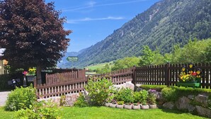 A garden with a pond, a wooden fence, and a sign for 'Haus DANKL Apartments'. - Apartement Haus Dankl by Interhome (Fusch)