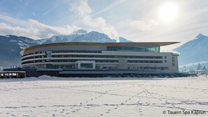 A modern building with a curved roof, surrounded by snow and mountains. - Apartement Haus Dankl by Interhome (Fusch)