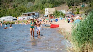 A beach scene with people walking in shallow water, tents, and beachgoers in the background. - Fantastic time-out vacations for families - fun and relaxation for young and old! (Bad Lauchstädt)