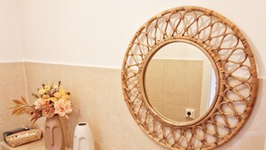 A bathroom with a round mirror, a vase with flowers, a white vase, and a reed diffuser on the counter. - Fantastic time-out vacations for families - fun and relaxation for young and old! (Bad Lauchstädt)