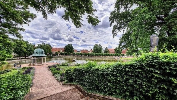 A garden pathway leading to a gazebo, surrounded by lush greenery and a pond. - Fantastic time-out vacations for families - fun and relaxation for young and old! (Bad Lauchstädt)