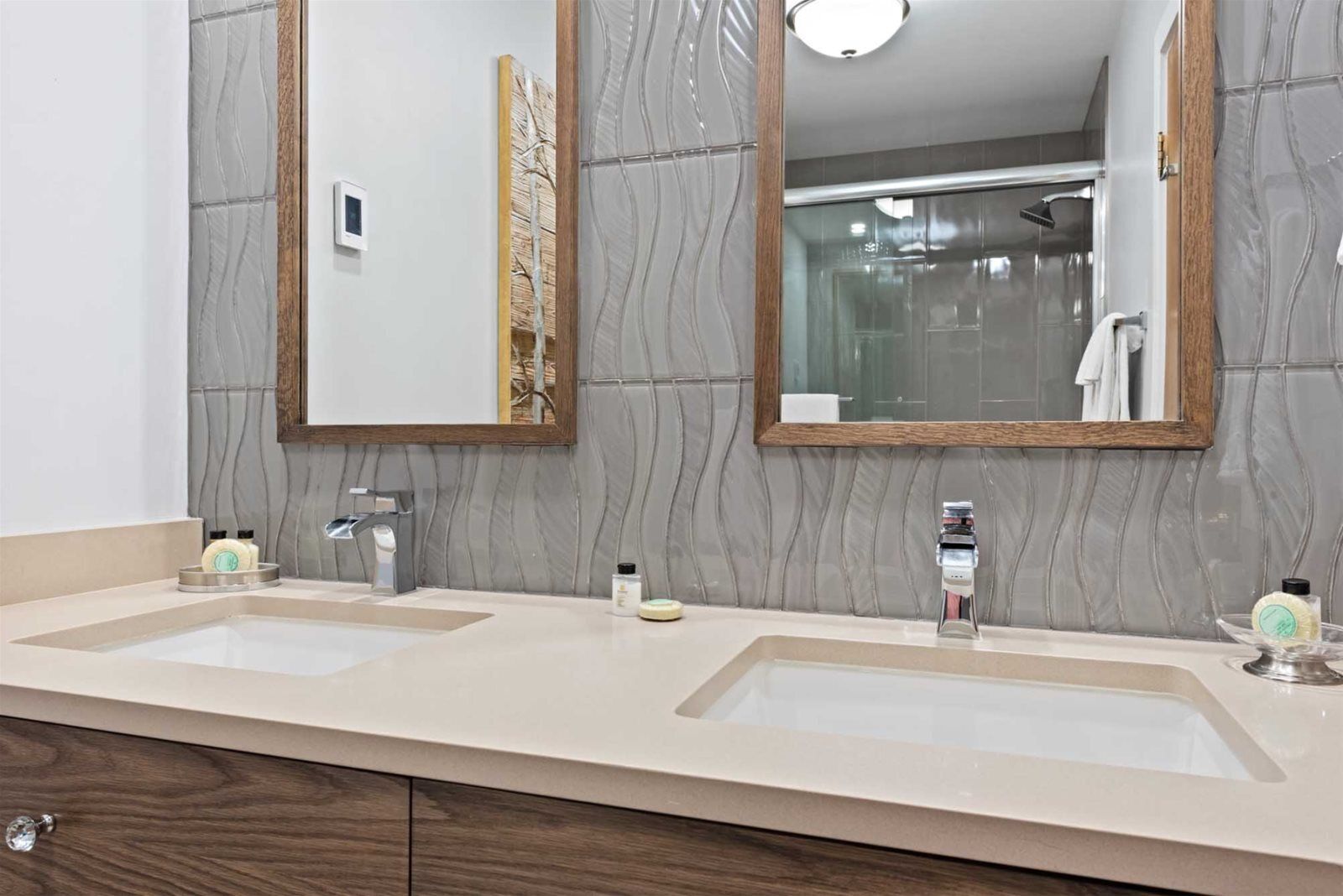 A bathroom with two sinks, a mirror, and a shower.