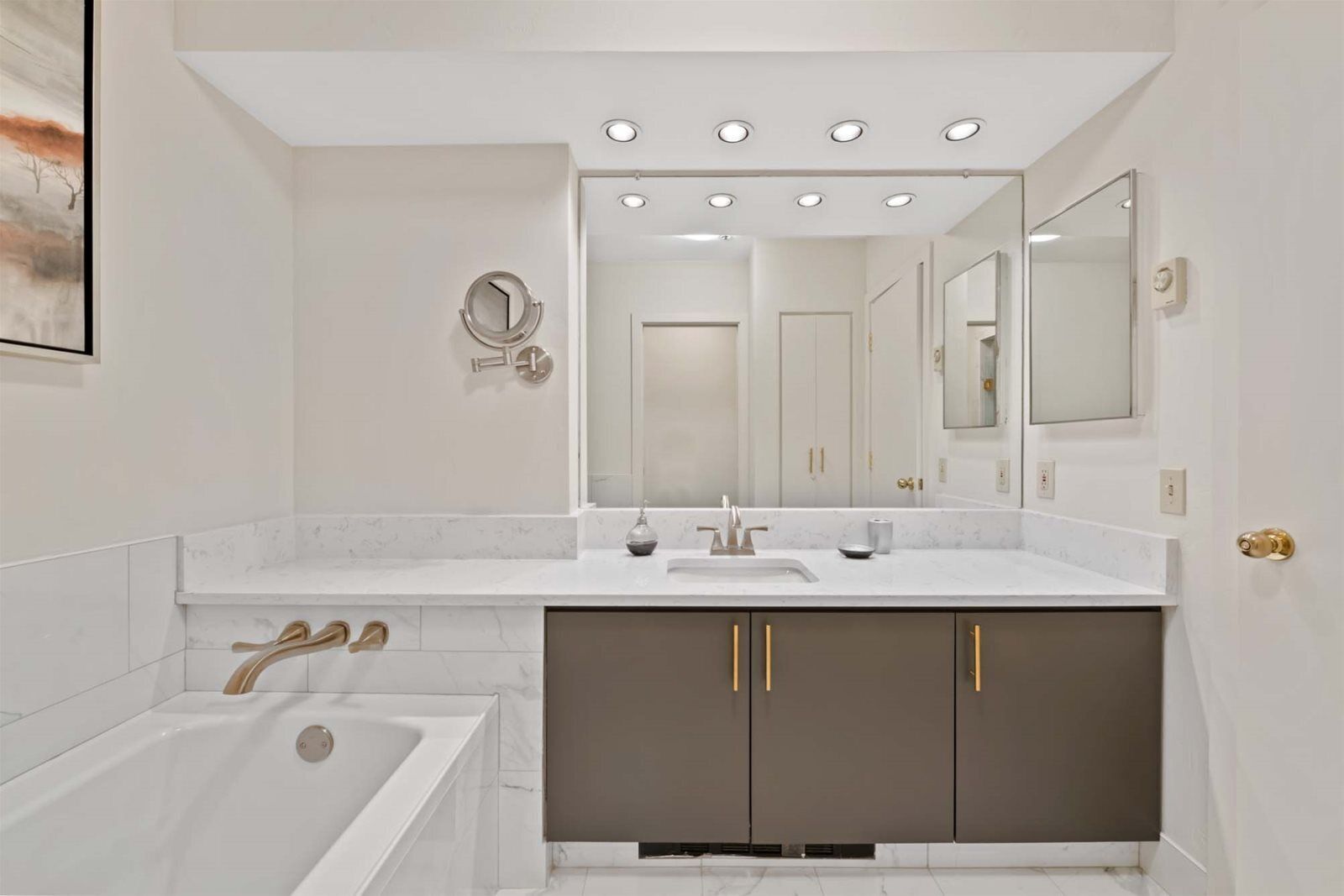 A modern bathroom with a bathtub, a sink, and a vanity with cabinets.