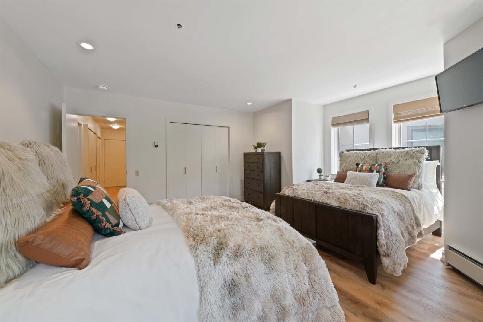 A bedroom with two beds, a wardrobe, and a TV.