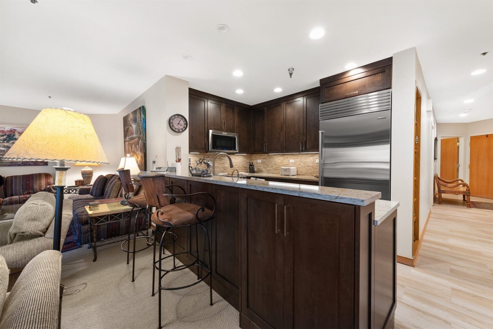 A modern kitchen with dark wood cabinets, stainless steel appliances, and a bar area with stools.