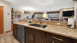 A modern kitchen with granite countertops, a built-in dishwasher, and a large island with a sink. - Beaver Creek Centennial 2 Bedroom #17 (Avon)
