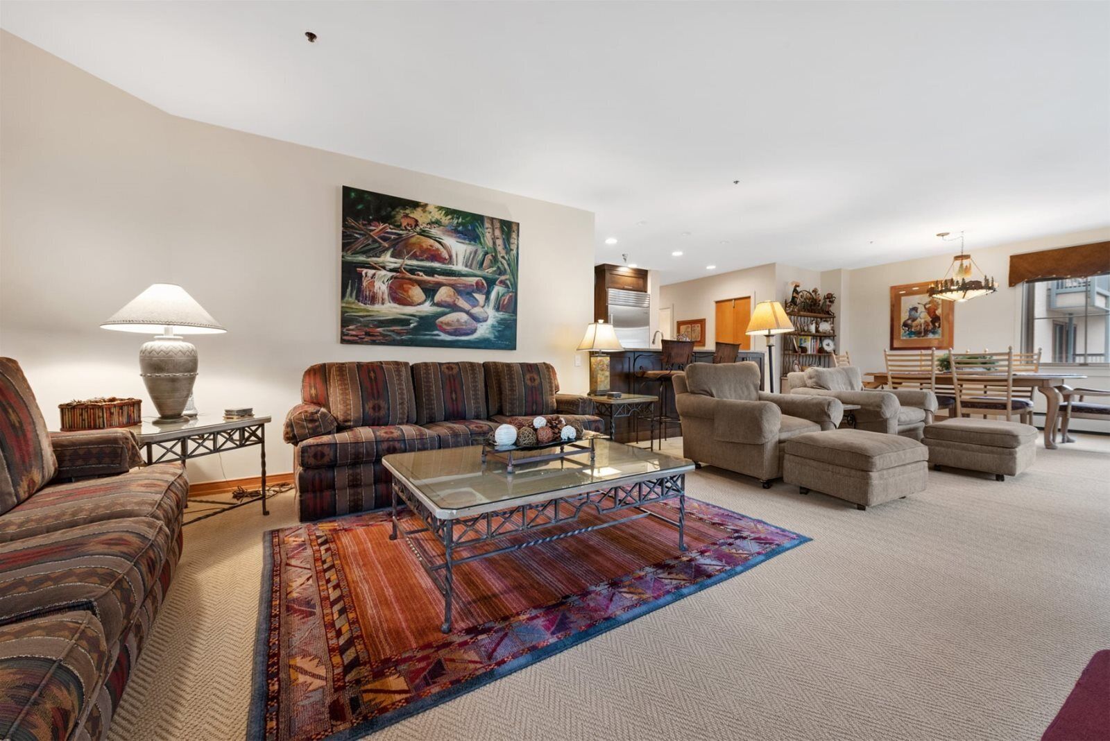 A spacious living room with a sectional sofa, a glass coffee table, and a dining area with a wooden table and chairs.