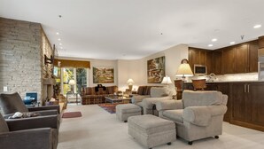 A modern living room with a fireplace, comfortable seating, and a kitchen area. - Beaver Creek Centennial 2 Bedroom #17 (Avon)