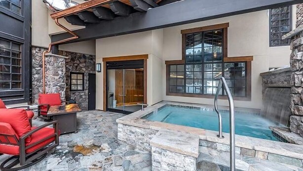 A modern outdoor pool area with stone flooring, a hot tub, and red seating. - Beaver Creek Village Ski In, Ski Out 3 Bedroom (Avon)