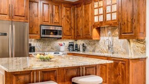 A kitchen with wooden cabinets, a stainless steel refrigerator, a microwave, and a granite countertop. - Beaver Creek Village Ski In, Ski Out 3 Bedroom (Avon)