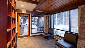 A lobby with a wooden ceiling, a stone wall, and a large window with a view of a snowy landscape. - Snowmass Village 1 Bedroom Premier Condo at Crestwood (Snowmass Village)