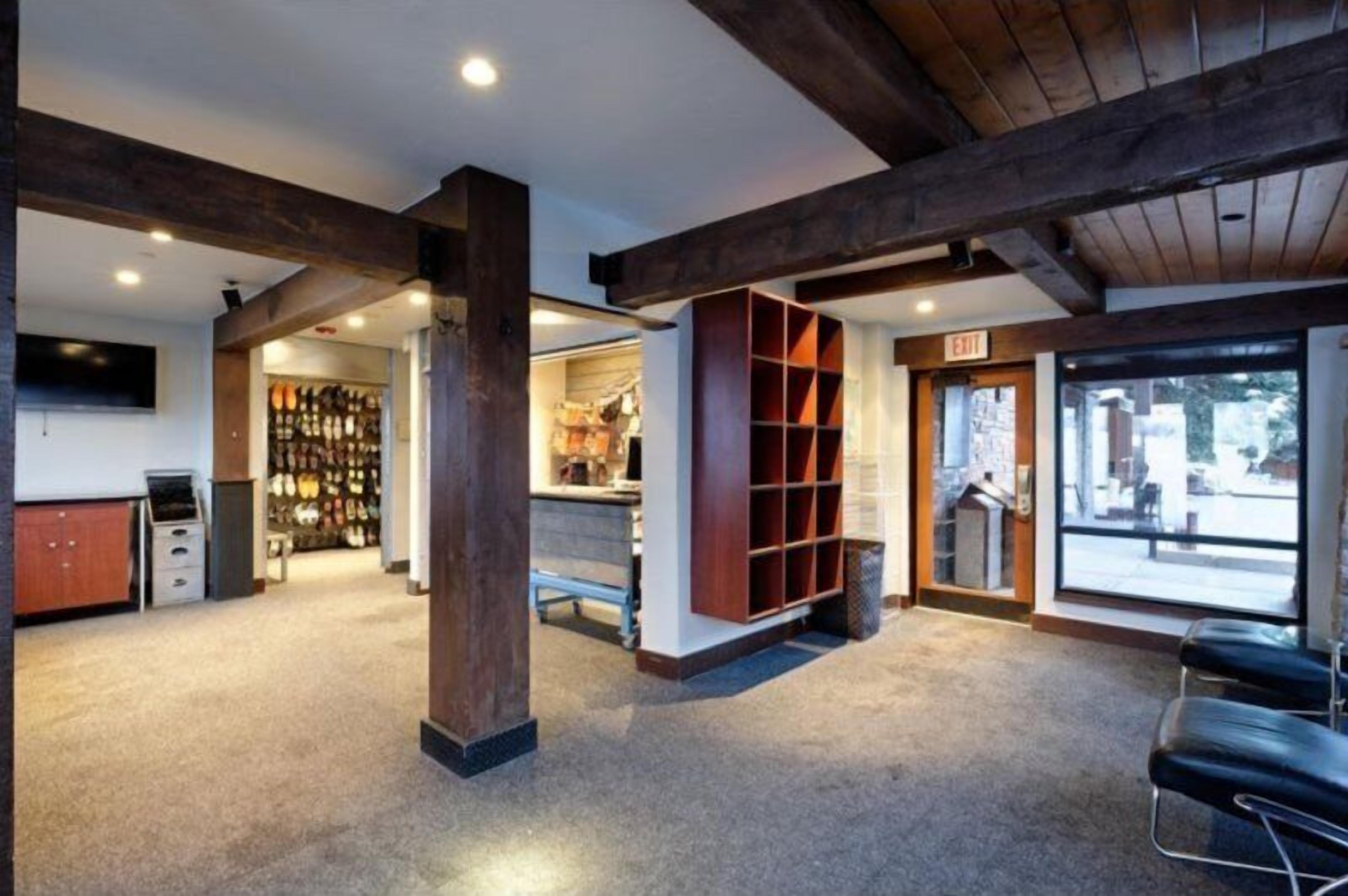 A spacious lobby with a high ceiling, wooden beams, a seating area, and a view through large windows.