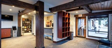 A spacious lobby with a high ceiling, wooden beams, a seating area, and a view through large windows.