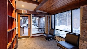 A lobby with a wooden ceiling, a stone wall, and a large window with a view of a snowy landscape.