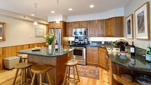 A modern kitchen with wooden cabinets, stainless steel appliances, and a central island with stools.