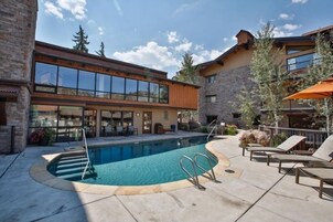 Un edificio moderno con piscina, asientos al aire libre y fachada de piedra.