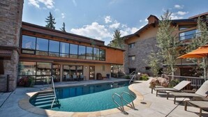 A modern building with a pool, outdoor seating, and a stone facade. - Snowmass Village 3 Bedroom Deluxe at Crestwood (Snowmass Village)