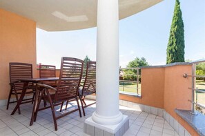 Relax in a serene outdoor space with a high ceiling, surrounded by a railing and a beautiful tree.