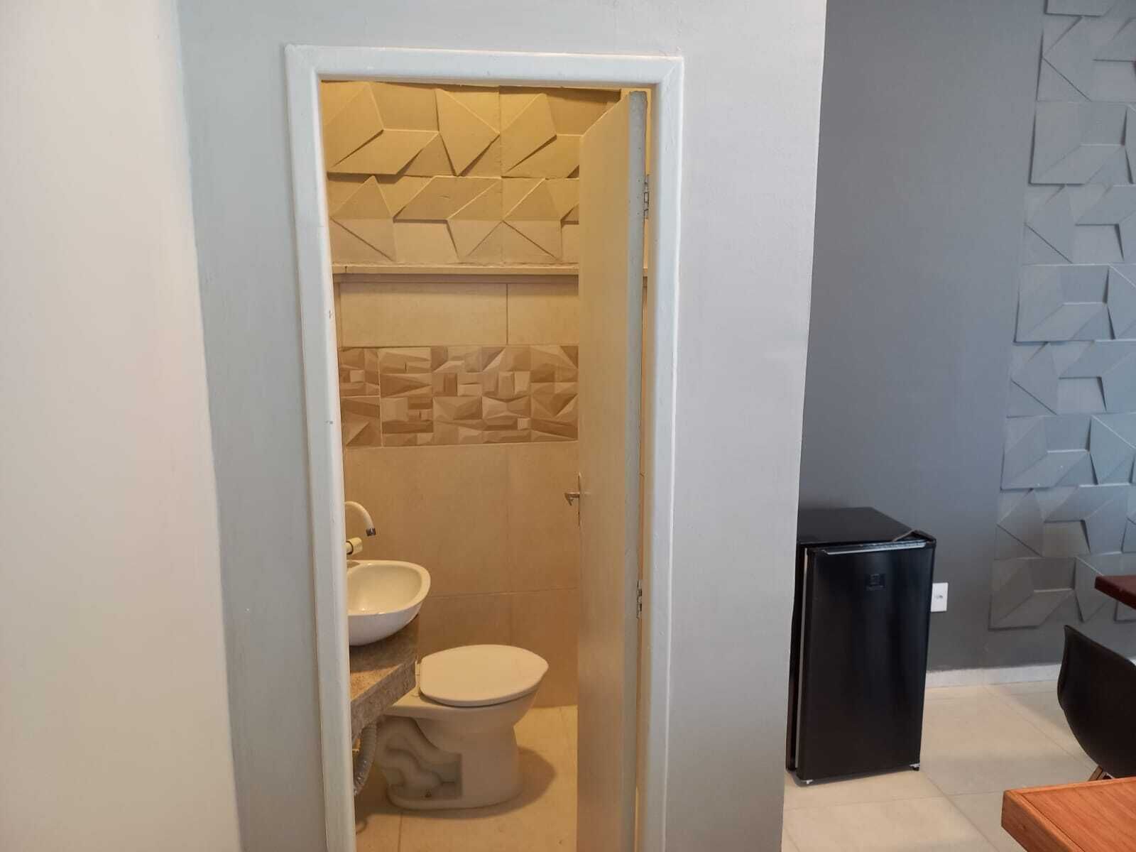 Ein Badezimmer mit Toilette, Waschbecken und einem schwarzen Kühlschrank.