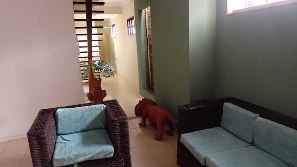 A room with two wicker sofas with blue cushions, a small red toy dinosaur, and a potted plant.
