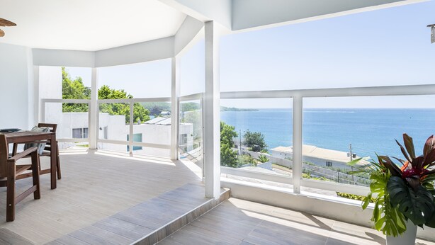 A spacious balcony with a view of the sea and a dining area with a table and chairs.