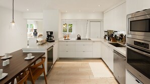 A modern kitchen with white cabinetry, a central island, and stainless steel appliances.