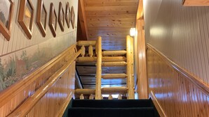 A wooden staircase with a handrail, carpeted steps, and a wall with framed pictures. - Mountain Cabin: 2 bed/2 bath, Fire pit, Close to Yellowstone and a moose family! (Island Park)