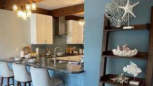 A modern kitchen with a bar area, wooden beams, and decorative shelves. - 04 Rustic meets beachy in Wilton Manors! (Wilton Manors)